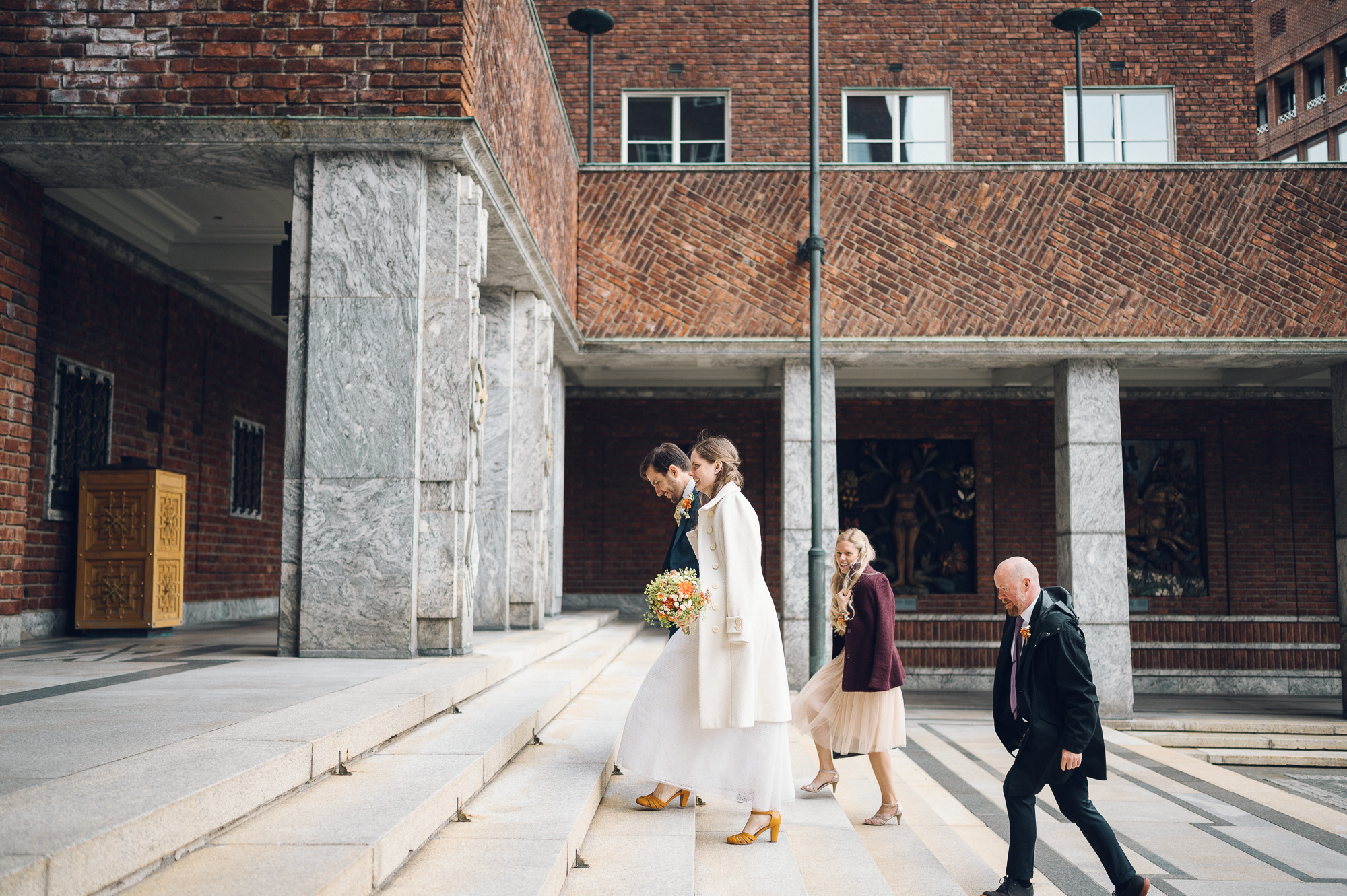 Bryllupsfoto av brud og brudgom som går opp trappa på rådhuset.