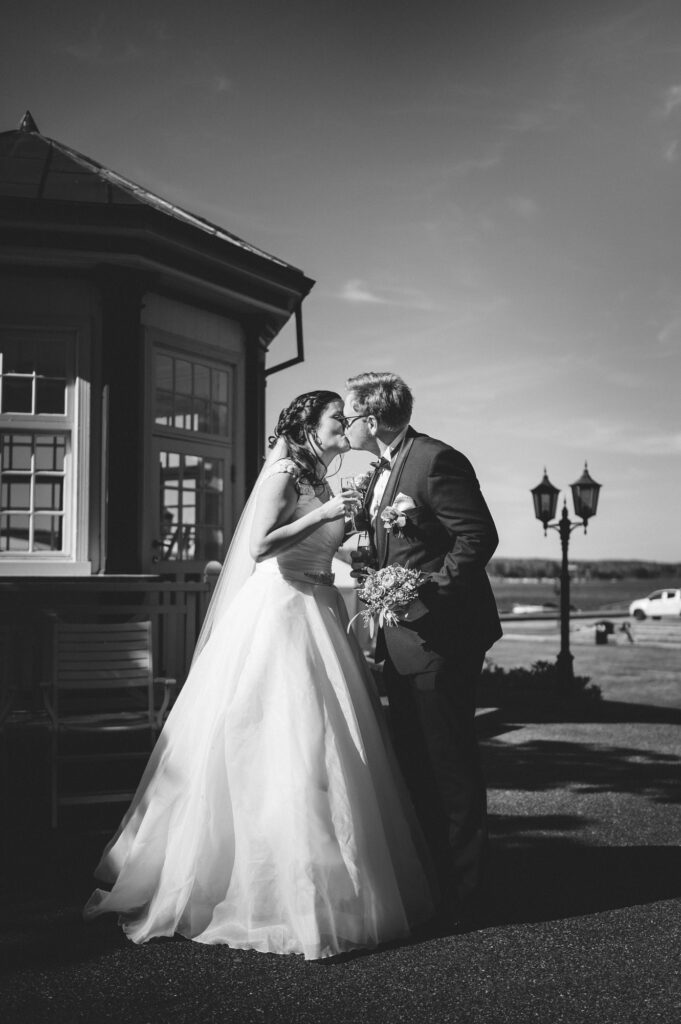 Brud og brudgom kysser hverandre med hver sin velkomstdrikk. De skal straks ha bryllupsmiddag på Tyrifjord hotell.