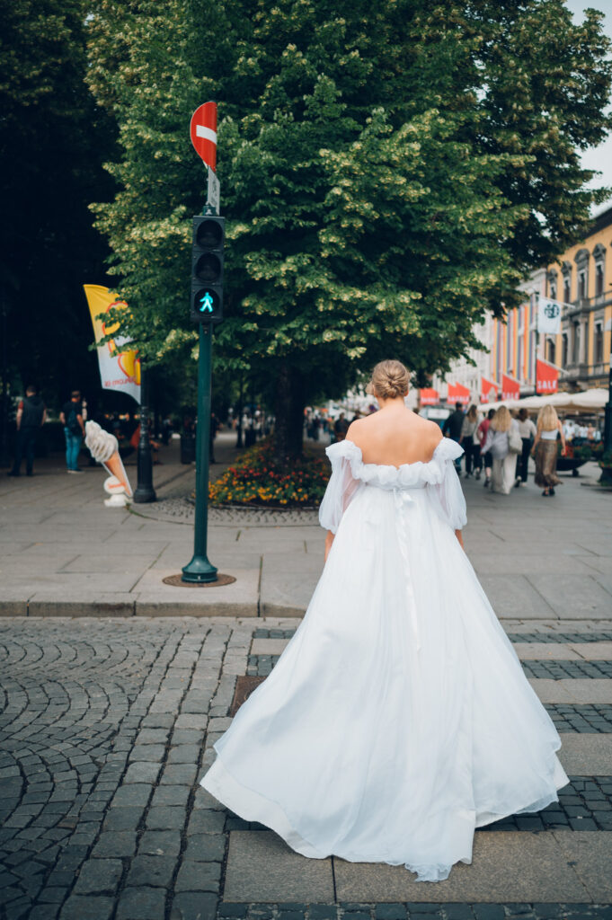 En brud med hvit brudekjole går over et fotgjengerfelt i Karl Johans gate i Oslo.